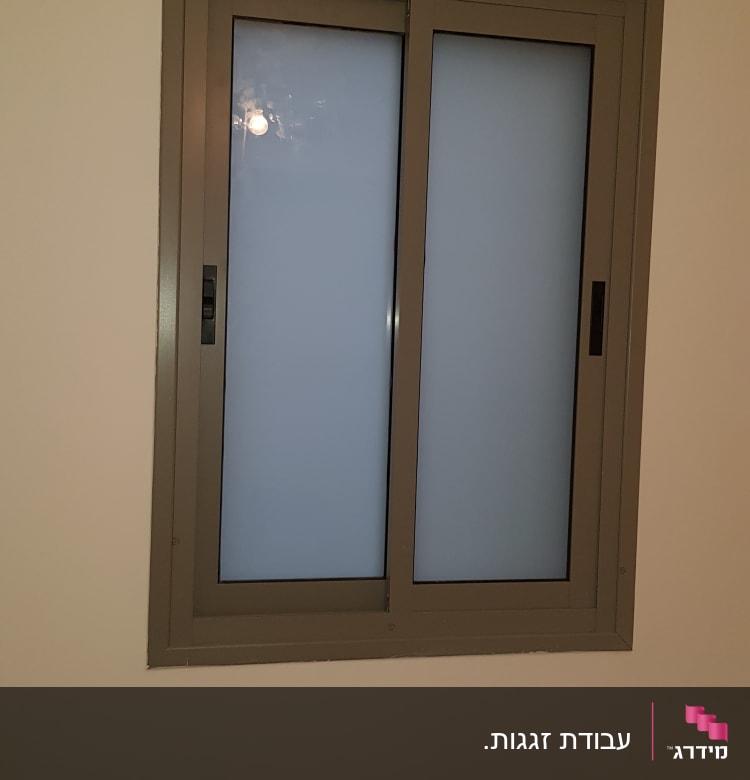 חלון זכוכית עם מסגרת מתכתית כהה